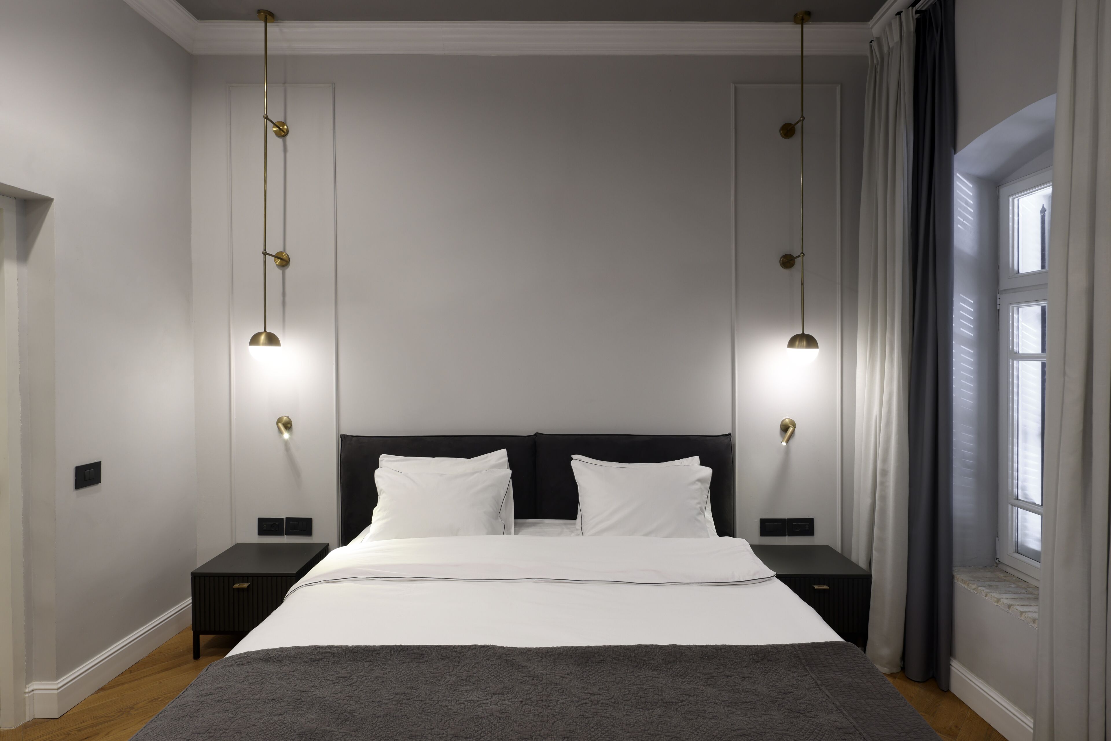 A modern bedroom with a large bed, two bedside tables, and a window with curtains.