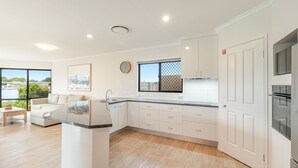 Uma cozinha moderna com armários brancos, uma janela ampla com vista e forno embutido.