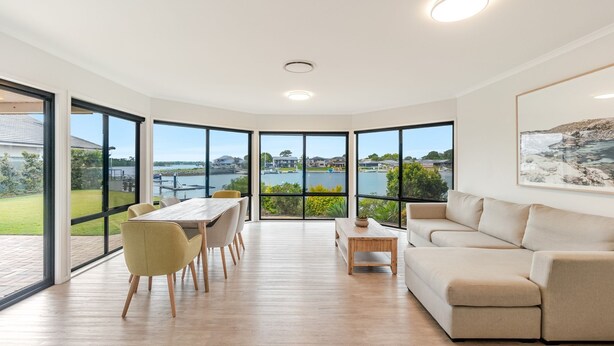 Uma sala de estar ampla com uma grande janela que oferece vista para um porto e casas.