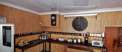 A kitchen with wooden cabinets, a built-in microwave, a coffee maker, and a clock on the wall.