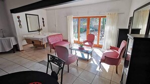 Una sala de estar con comedor, un juego de sofá, una mesa de centro y un amplio ventanal con cortinas.