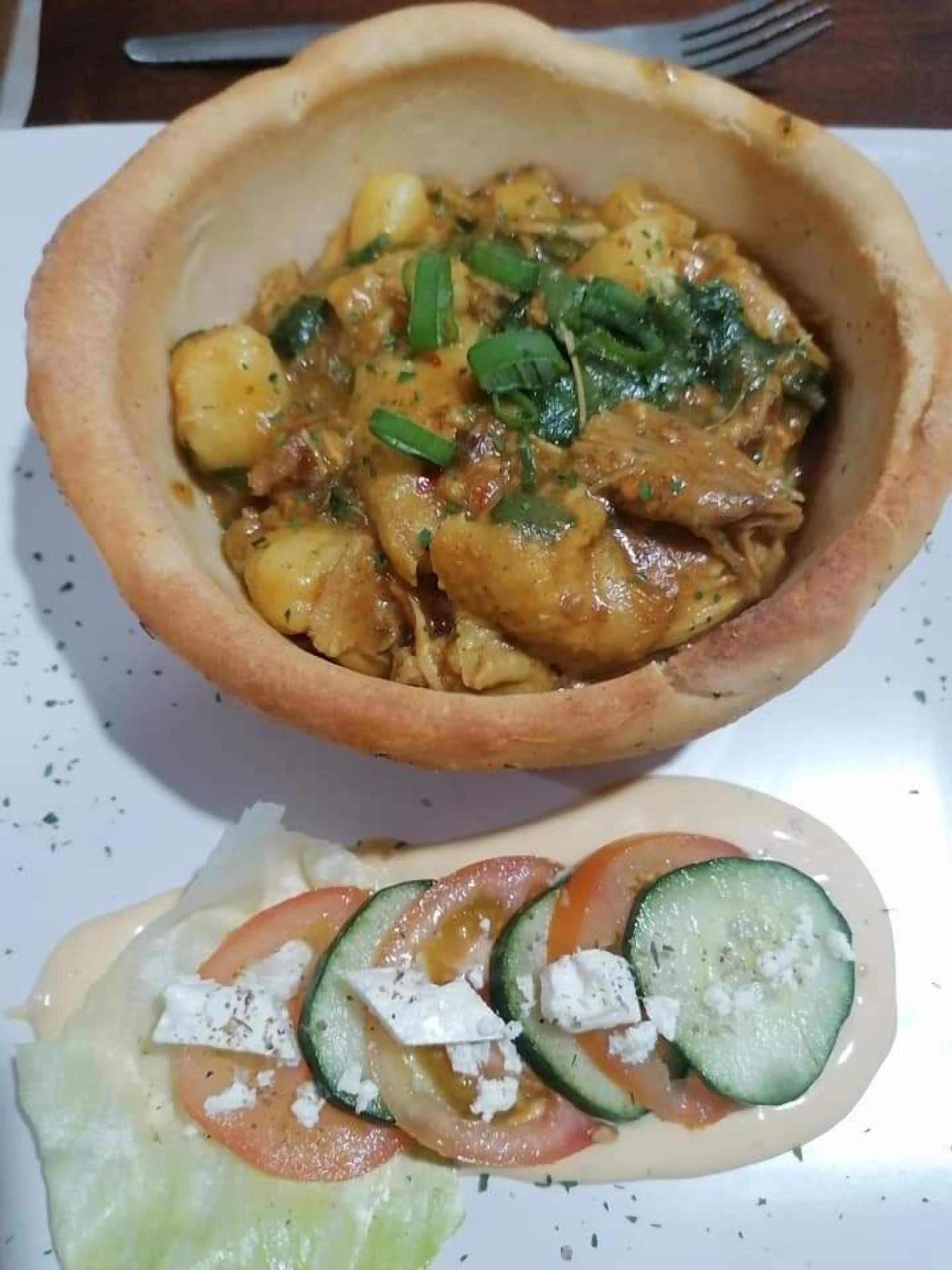A bowl of food with a side salad.