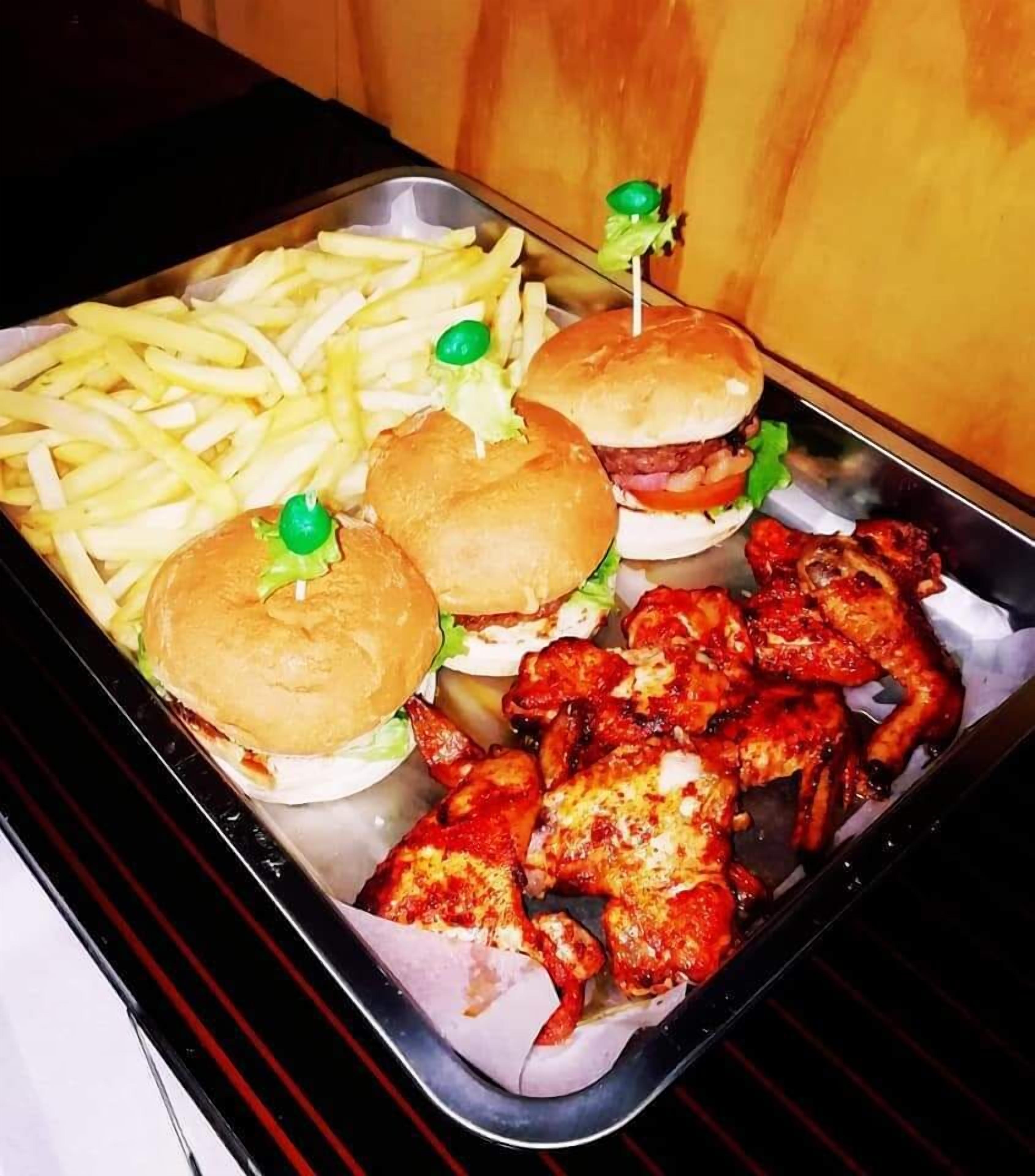 A tray with two burgers, a side of fries, and grilled chicken wings.