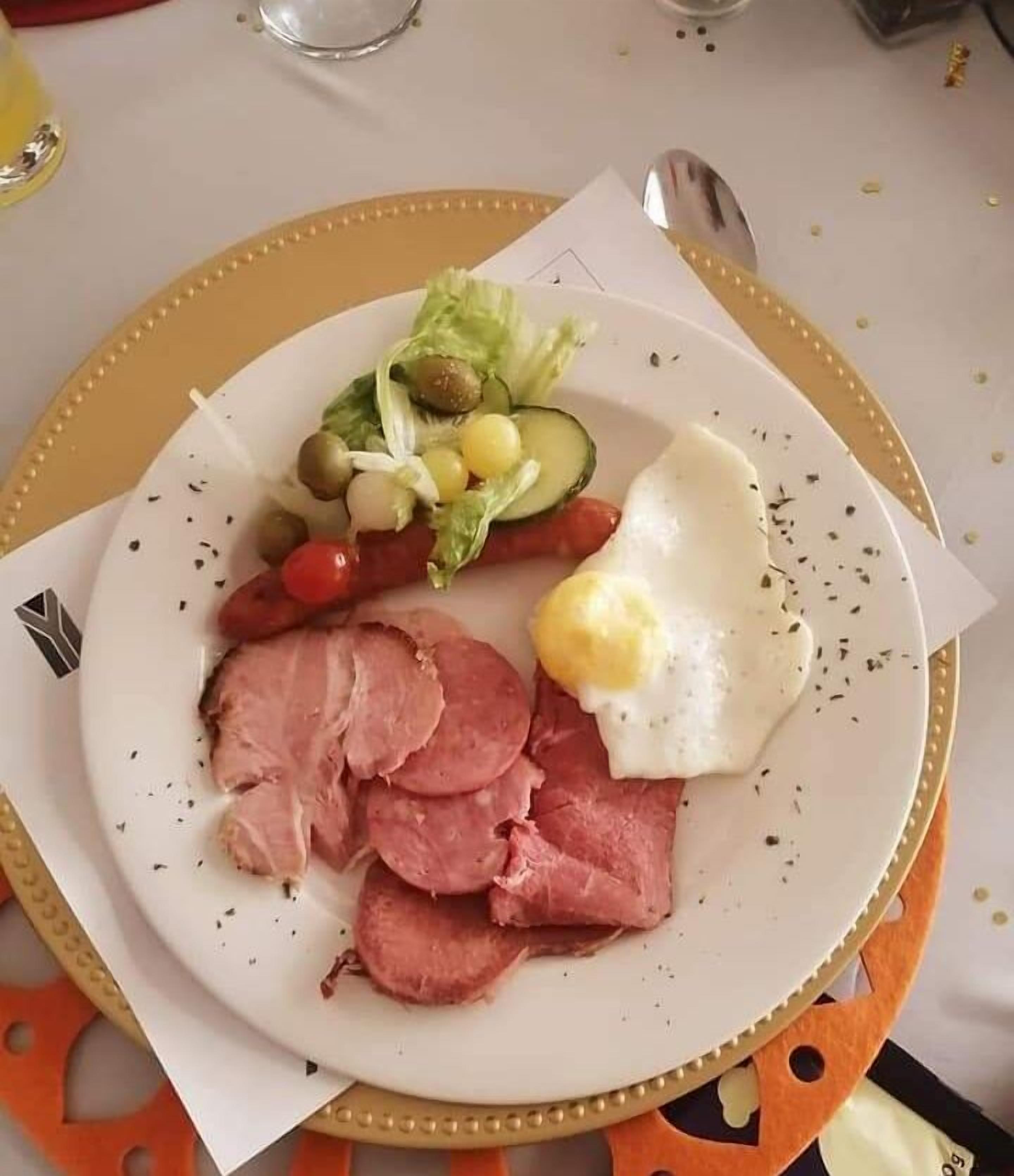 Ein Teller mit Scheibenkäse, einem Spiegelei und einem Beilagensalat.