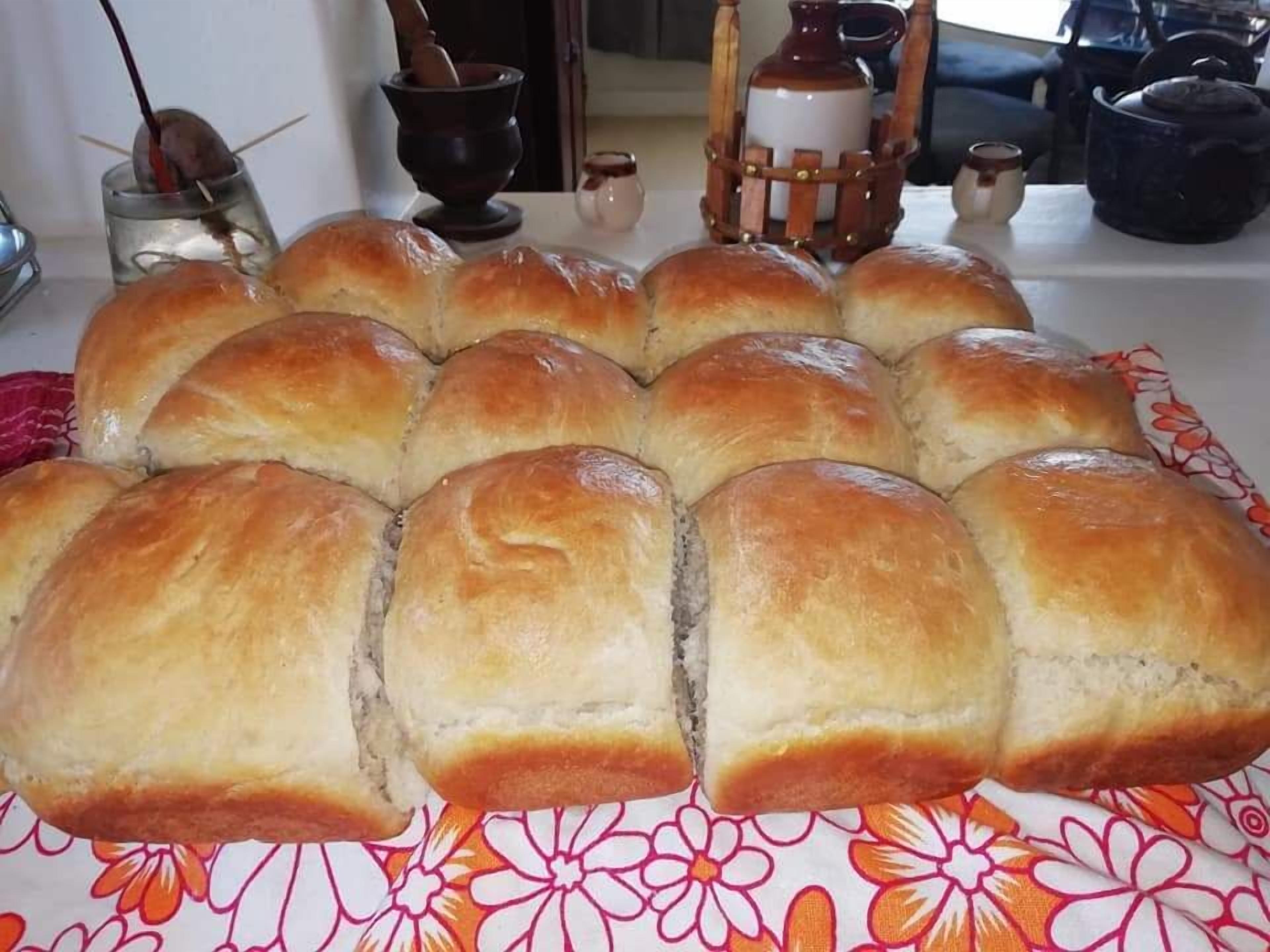 A table with a dozen golden-brown bread rolls arranged in a grid pattern.