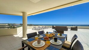 A terrace with a table set for breakfast, overlooking a beach and ocean. - ★Luxury Penthouse w/Stunning Sea Views, Walk Beach (Albufeira)
