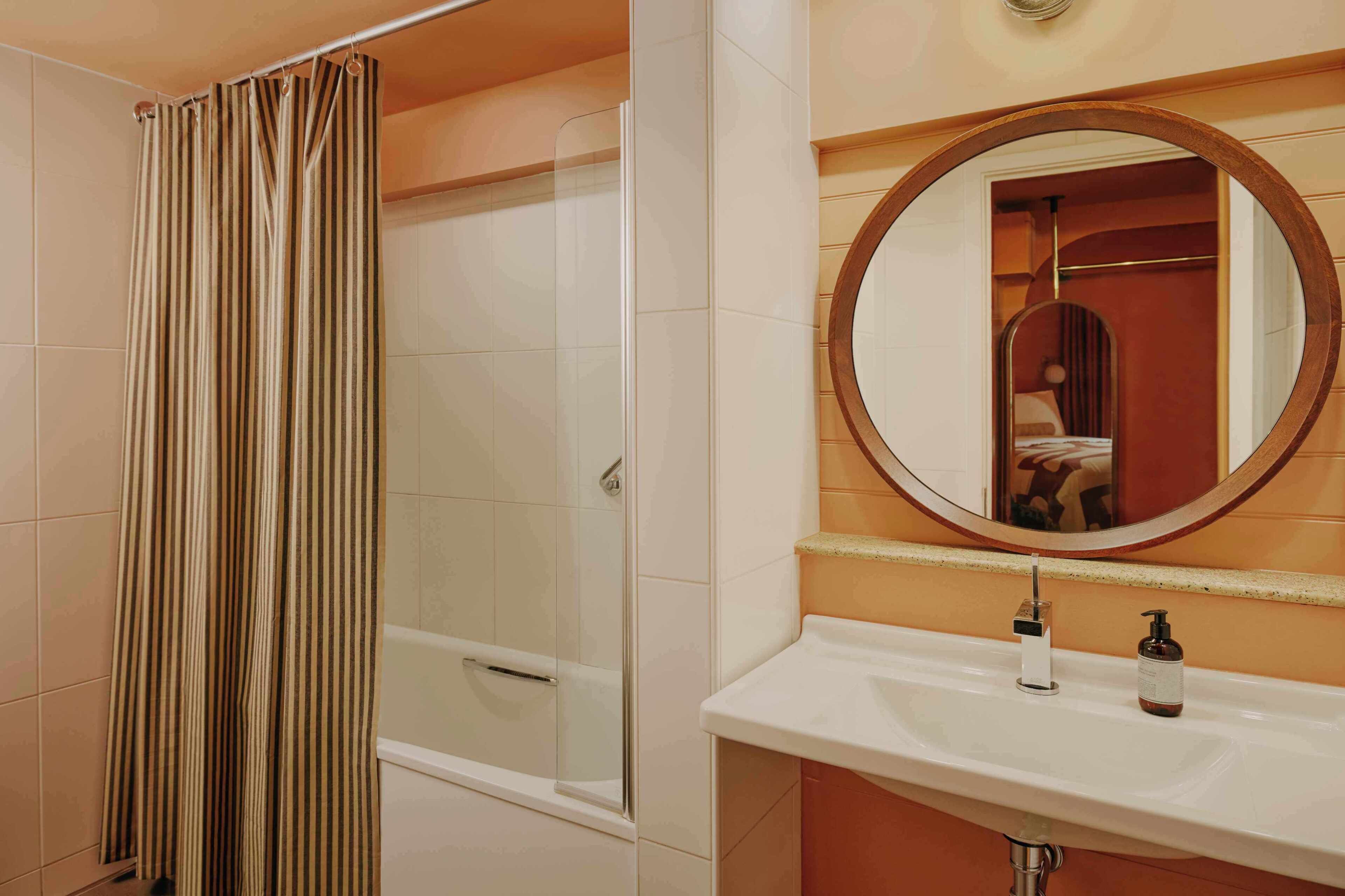 Un bany amb dutxa, un lavabo, un mirall i una barra de tovalloles.