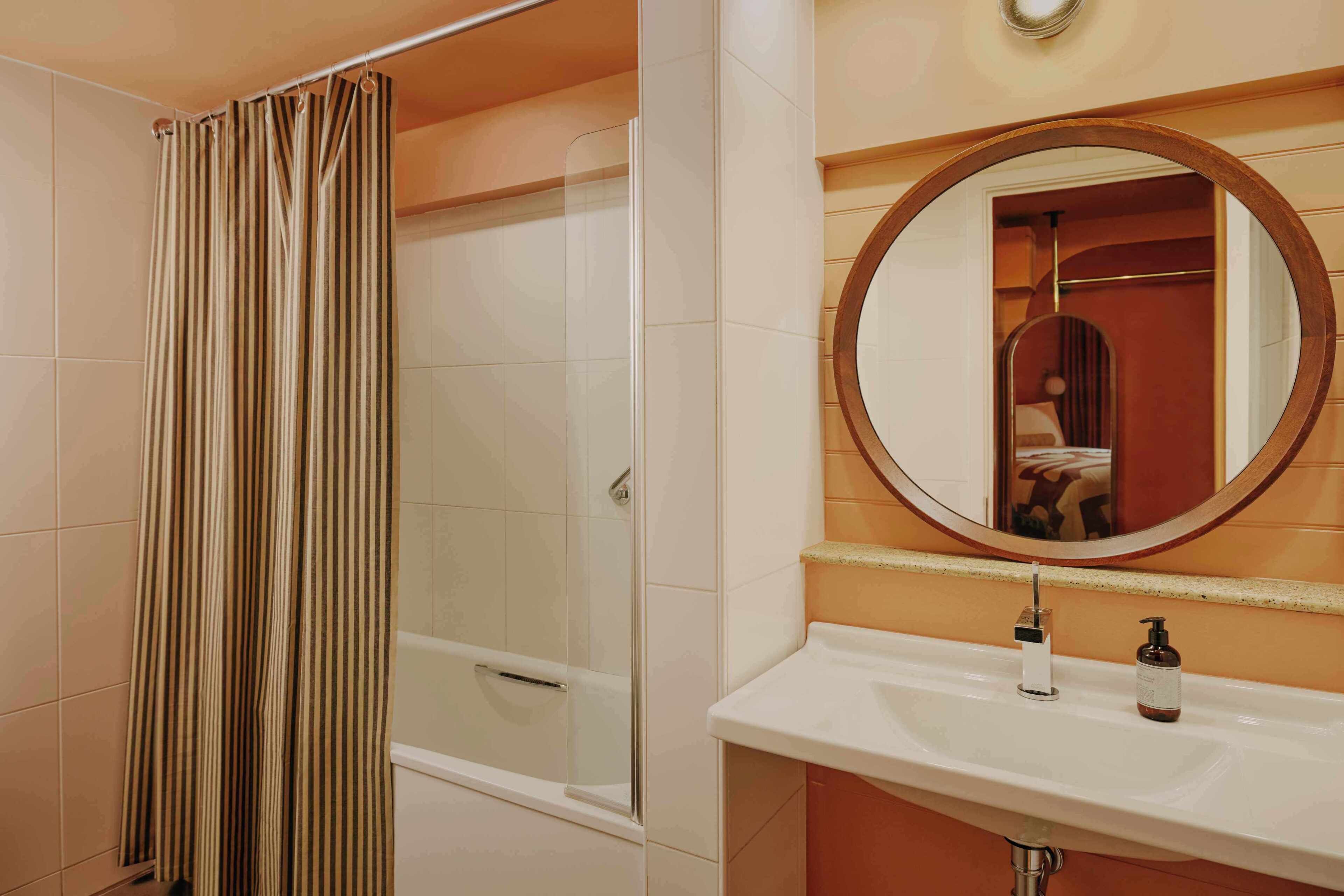 A bathroom with a shower, a sink, a mirror, and a bottle of soap.