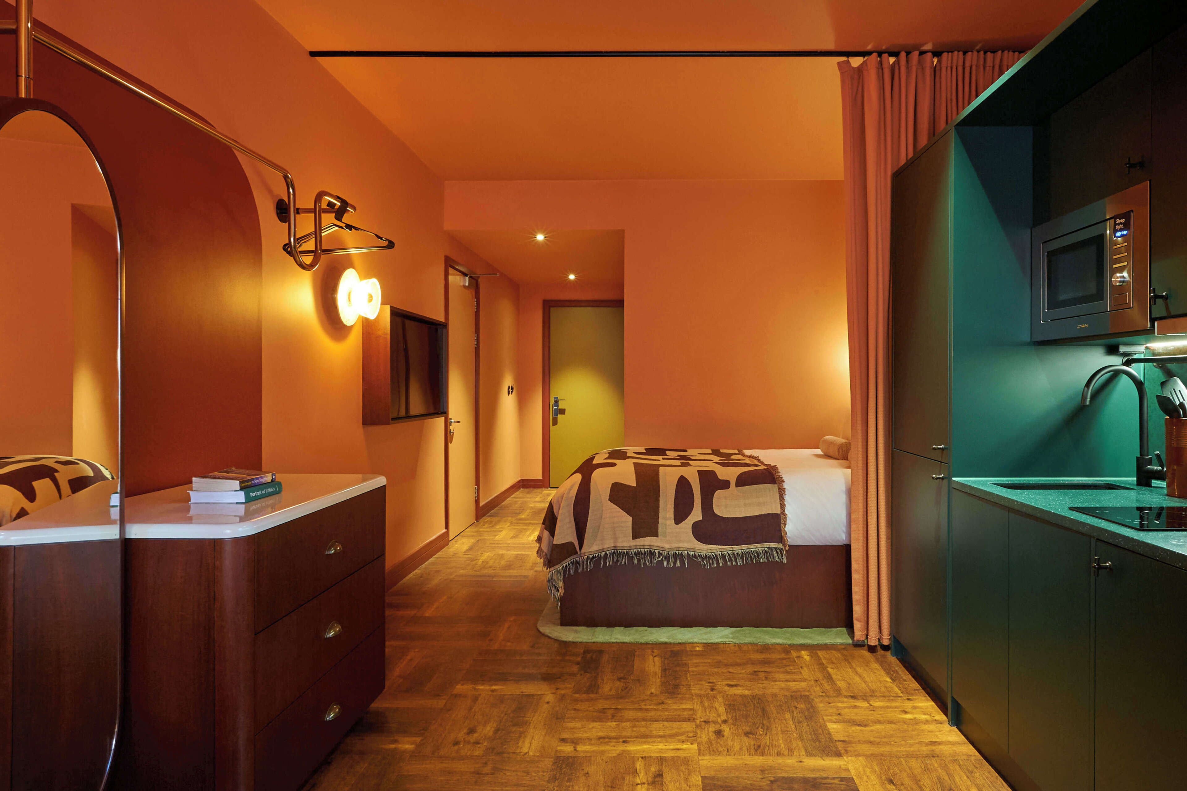 Ein Hotelzimmer mit einem Bett, einem Schreibtisch mit Schubladen, einem Spiegel, einer Mikrowelle und einem Waschbecken.