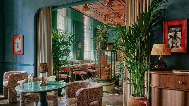 A room with a round table, chairs, a cabinet, and potted plants. - Ember Locke Kensington (London)