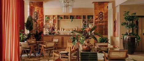 A spacious room with a dining area, a kitchen with shelves, and a large potted plant.