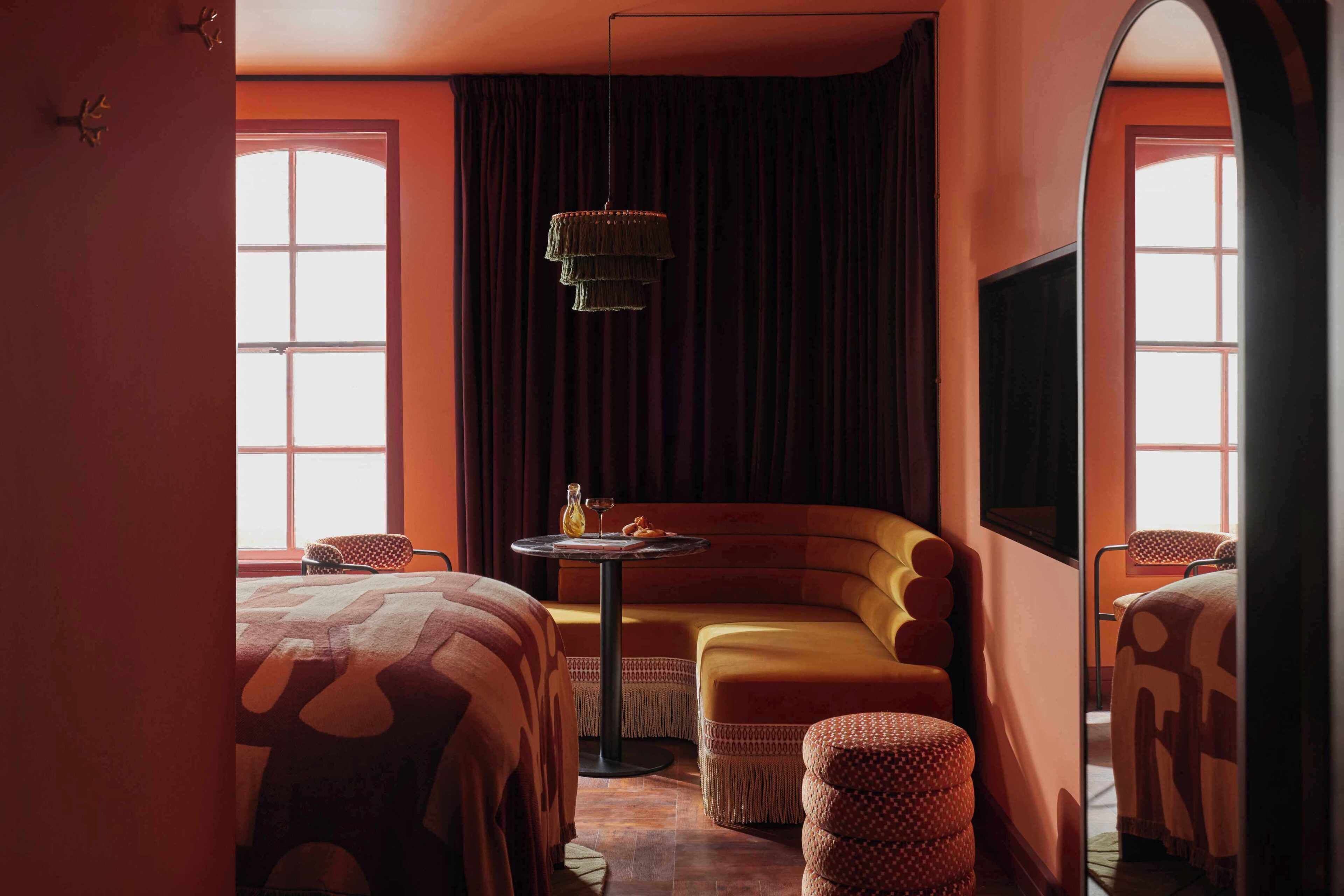 A room with a sofa, two beds, a small table, and a TV.