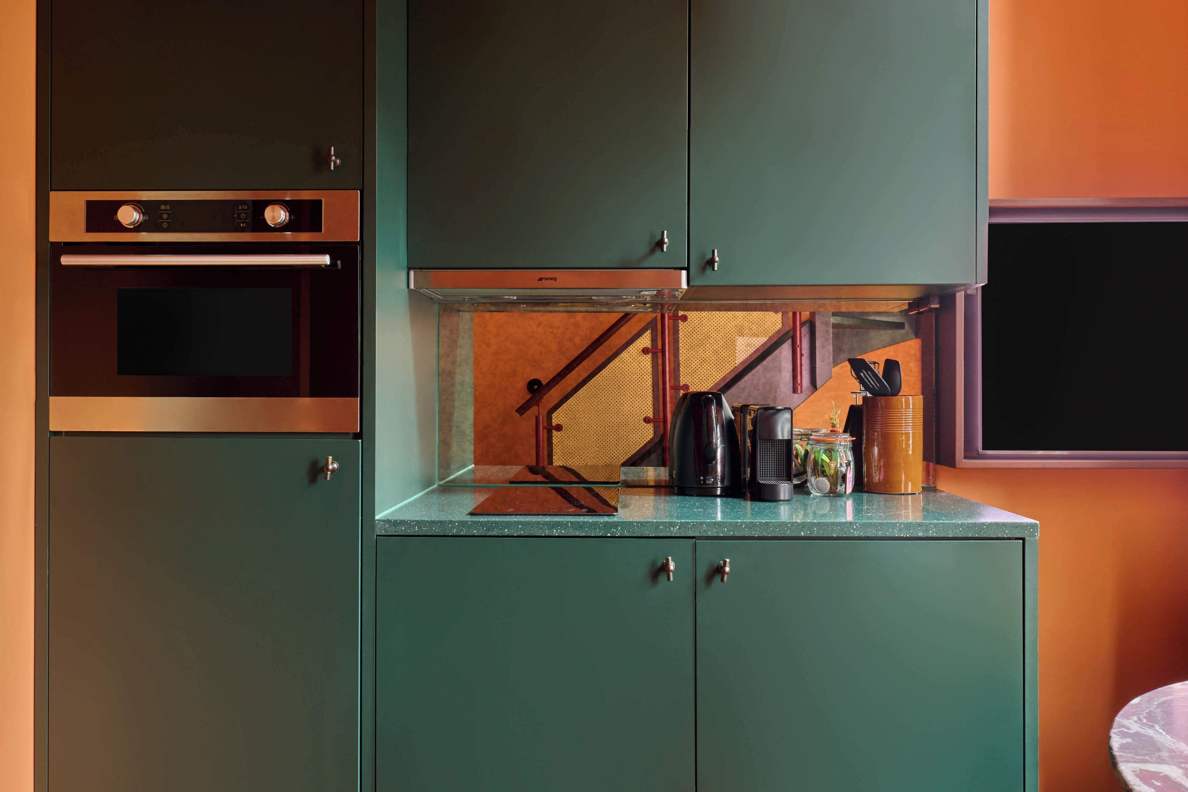A kitchen with a built-in oven, a coffee maker, and a small table with jars.