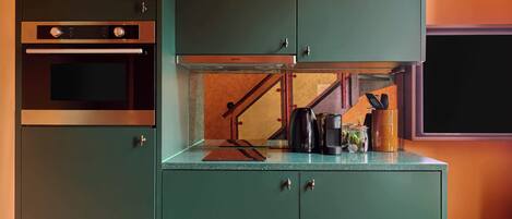 A kitchen with a built-in oven, a coffee maker, and a small table with jars.