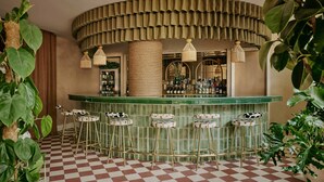 A bar area with a checkered floor, green bar counter, and three stools. - Ember Locke Kensington (London)