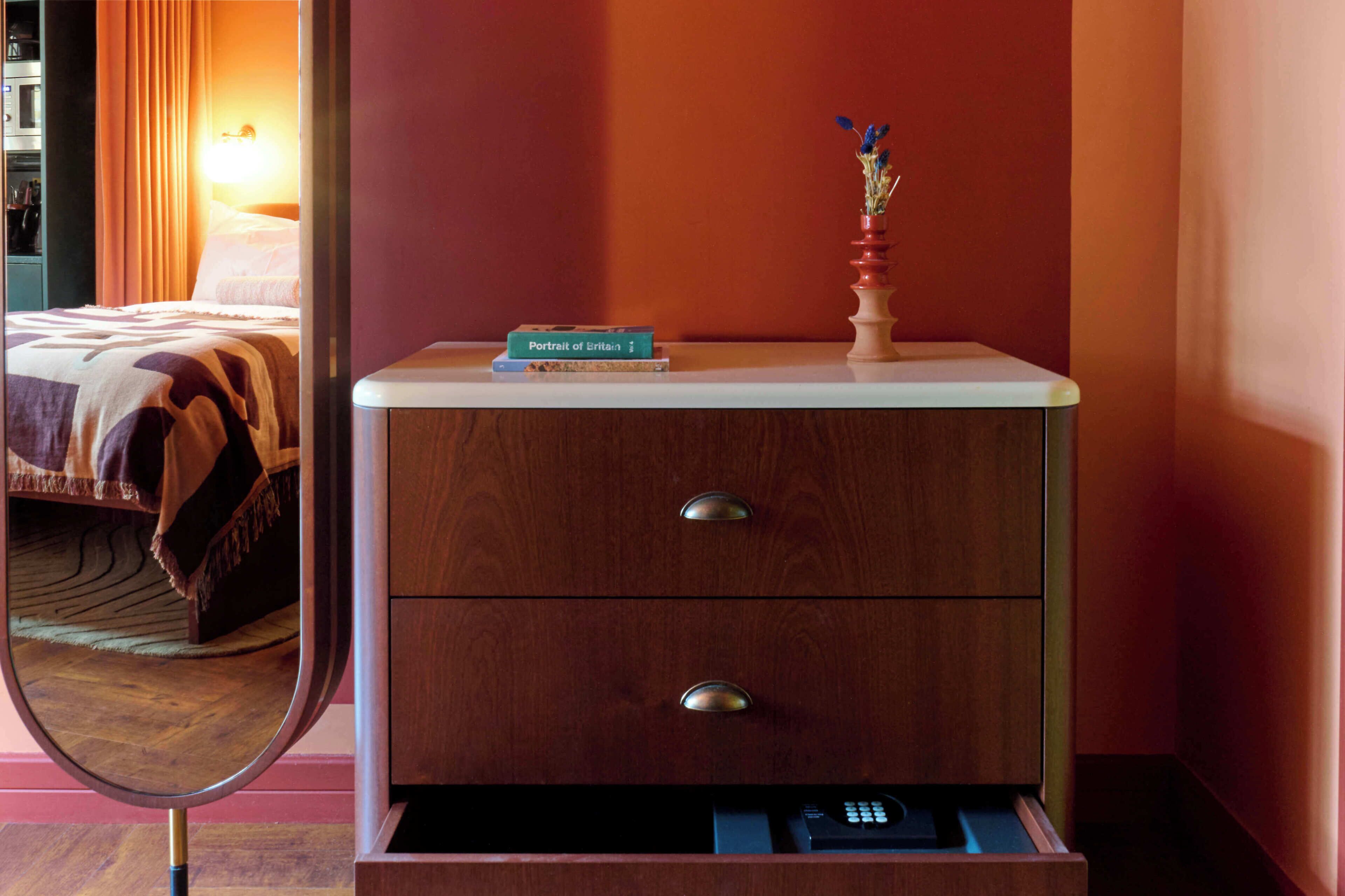A wooden dresser with two drawers and a small vase with flowers on top.