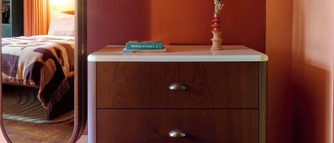 A wooden dresser with two drawers and a small vase with flowers on top.
