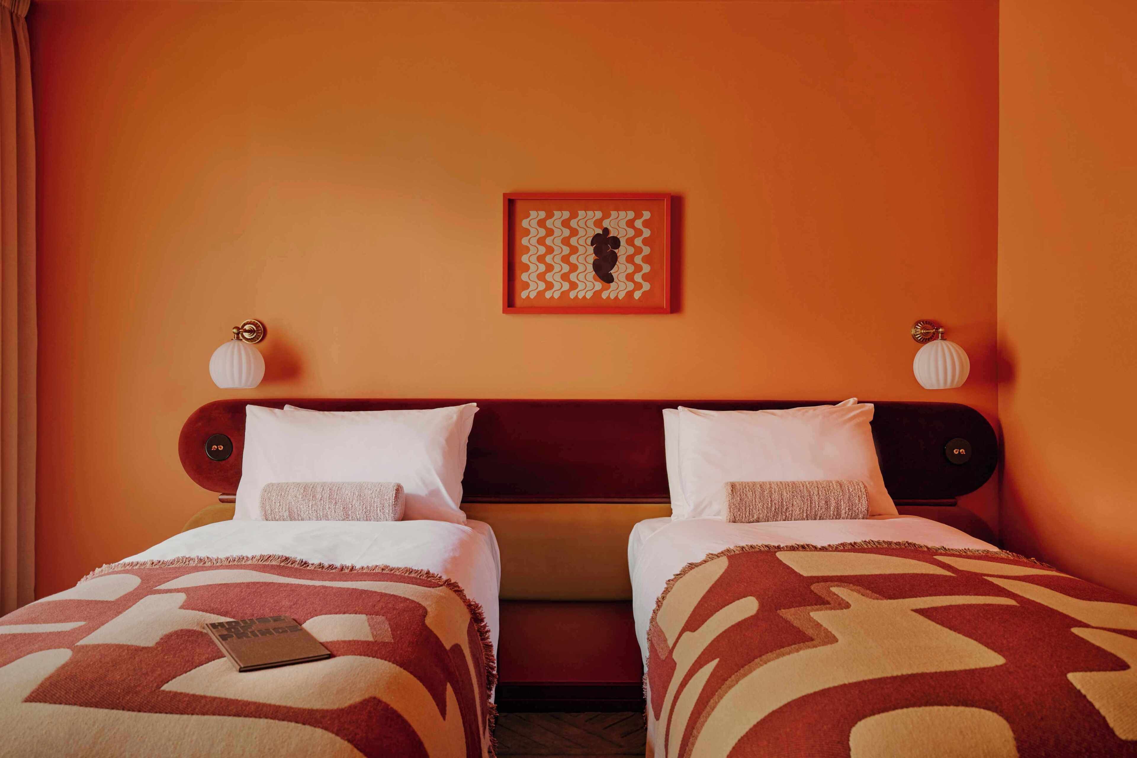 Una cama doble con una colcha estampada, una obra de arte enmarcada en la pared y dos lámparas fijadas a la pared.