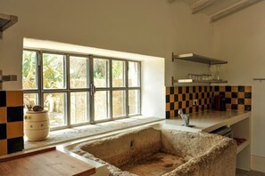 Cozinha com uma janela grande, ladrilhos quadriculados no painel e uma pia de pedra.