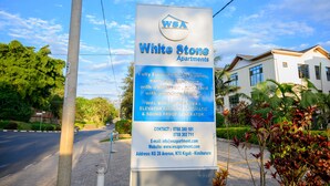 A sign for White Stone Apartments detailing amenities like WiFi, DSTV, CCTV camera, elevator, and soundproof generator. - White Stone Apartment KIMIHURURA (Kigali)