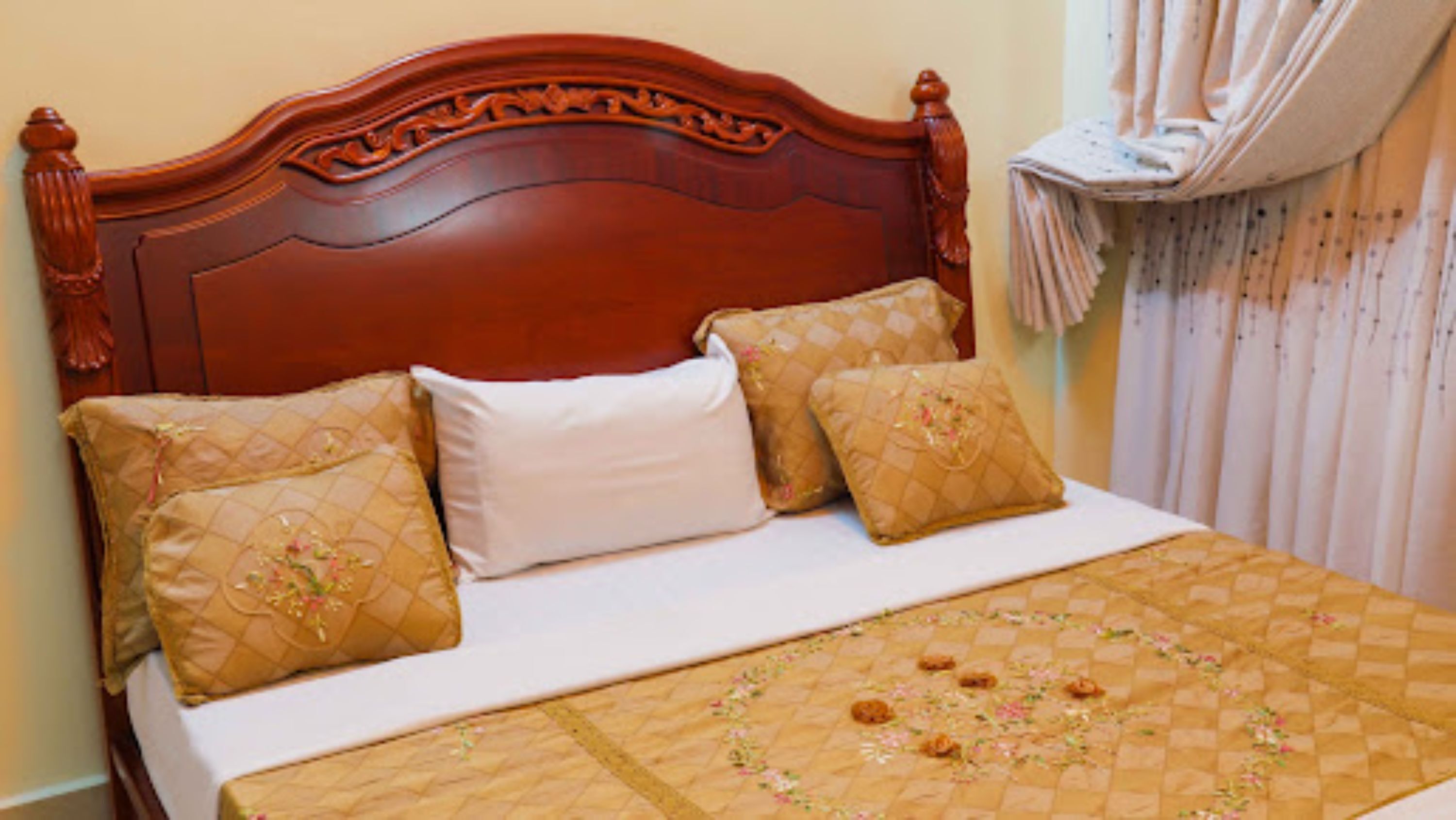 Una cama con cabecera de madera, tres almohadas y una colcha acolchada.