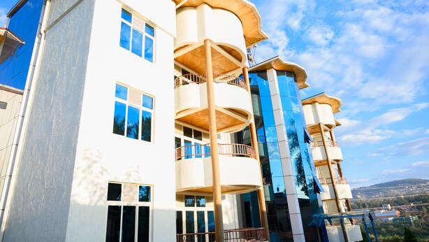 A multi-story building with balconies, large windows, and a clear sky. - White Stone Apartment KIMIHURURA (Kigali)