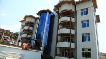 Un edificio de varios pisos con balcones, fachada de vidrio central y techo plano.