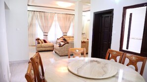 A dining area with a marble table and wooden chairs. - White Stone Apartment KIMIHURURA (Kigali)