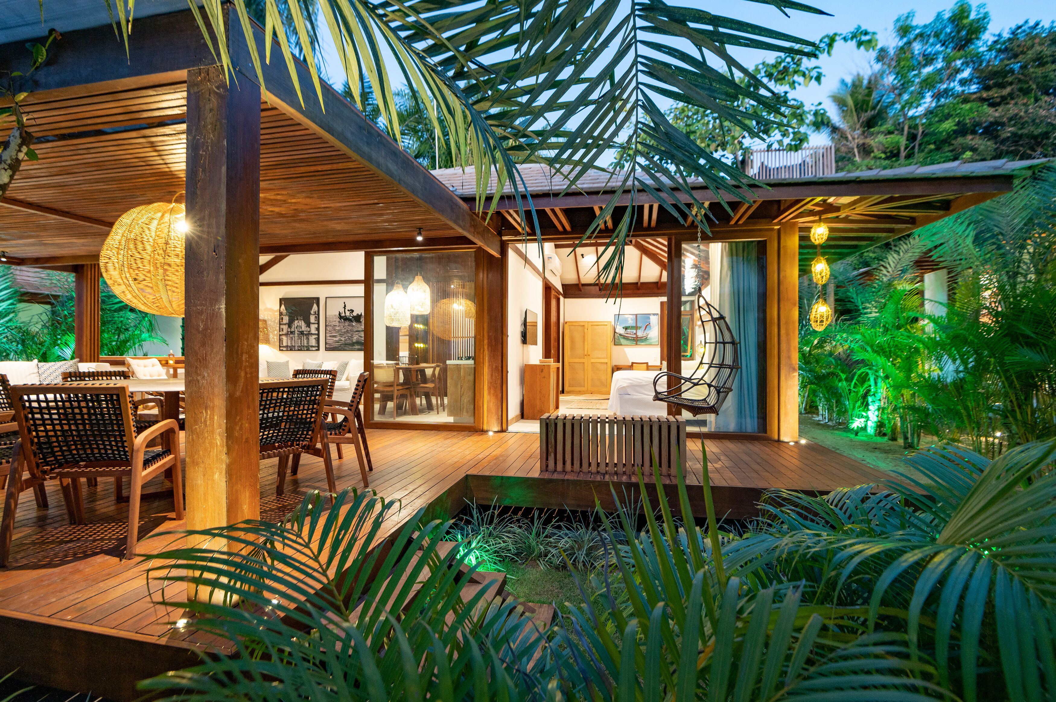 Un patio moderno al aire libre con piso de madera, muebles de mimbre y un espacio para sentarse.
