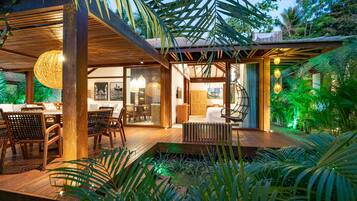 Un patio moderno al aire libre con piso de madera, muebles de mimbre y un espacio para sentarse.