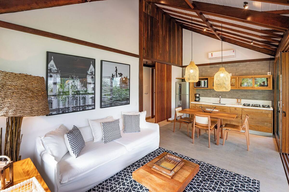 A modern living room with a white sofa, wooden dining table, and hanging wicker lamps.
