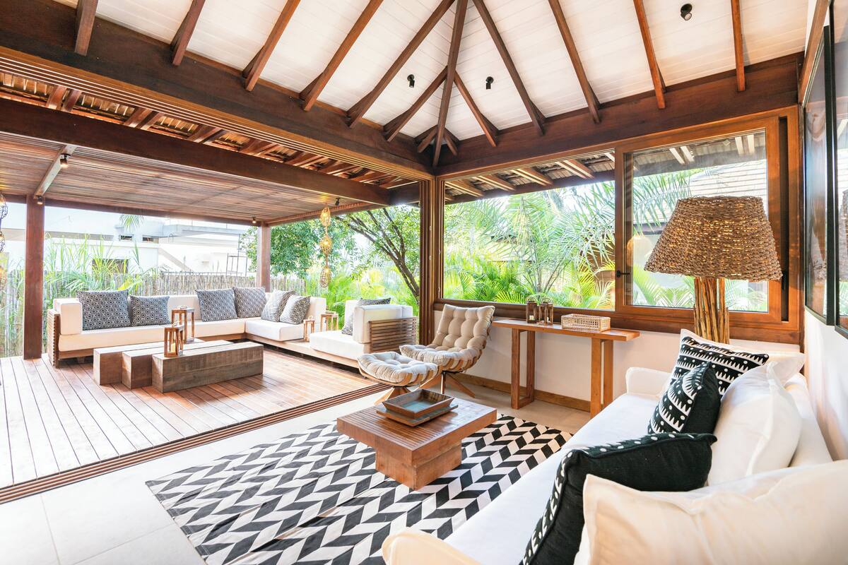 A spacious indoor area with a wooden ceiling, a sofa set, a coffee table, and a lamp.