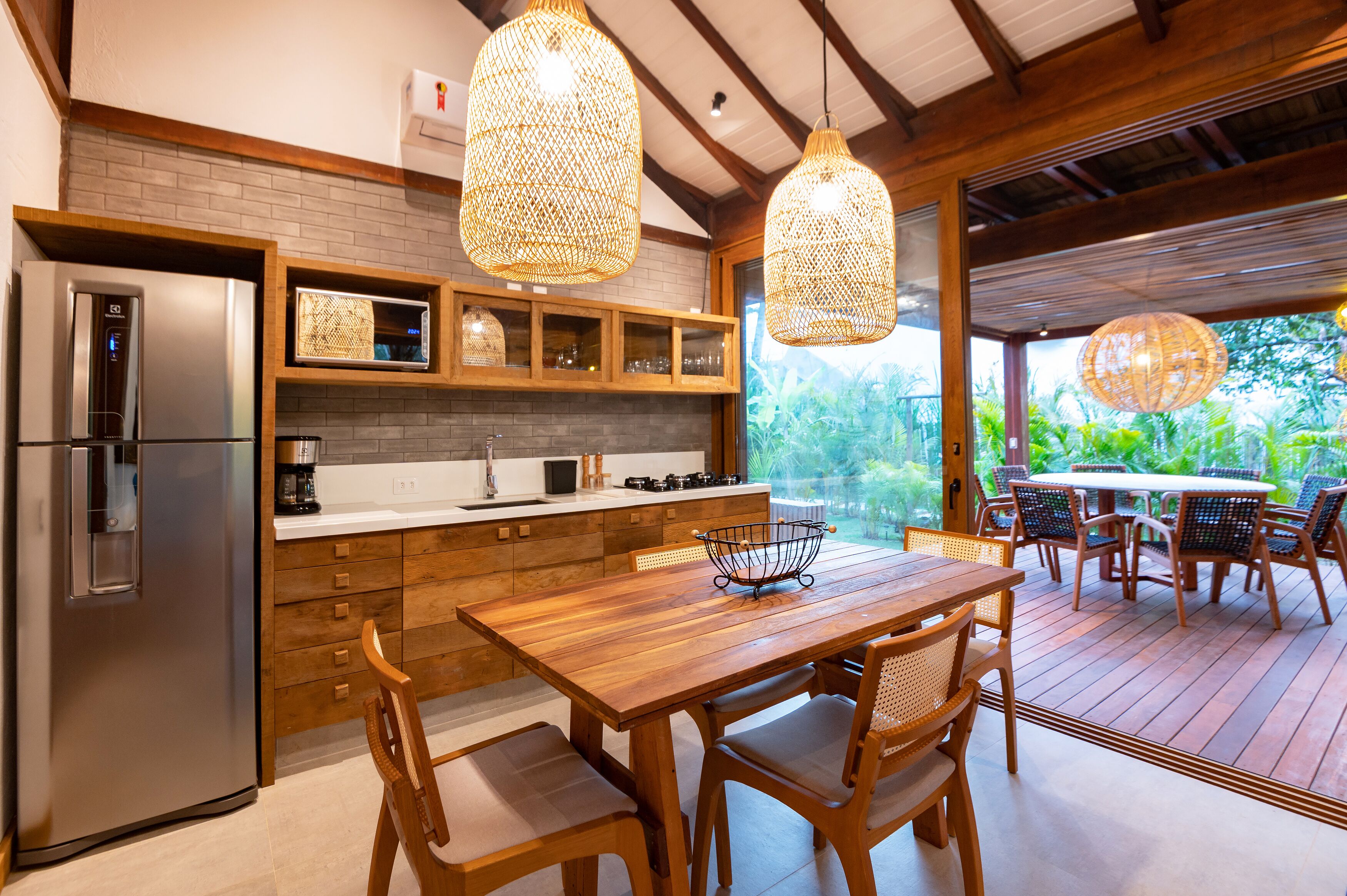 Una cocina moderna con refrigerador empotrado, armarios de madera y un comedor con mesa y sillas de madera.