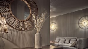 Een moderne woonkamer met een ronde spiegel, een vaas met gedroogde planten en een bank.