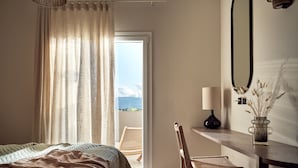 Een slaapkamer met een bed, een stoel, een bureau met een lamp, een vaas met planten en uitzicht op de omgeving.