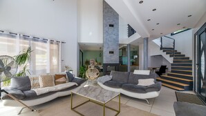 Amplia sala de estar con un moderno juego de sofá, una mesa de centro de mármol y una escalera que sube a un nivel superior.
