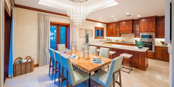 Una cocina moderna con armarios de madera, una isla central y un comedor con mesa y sillas de madera.