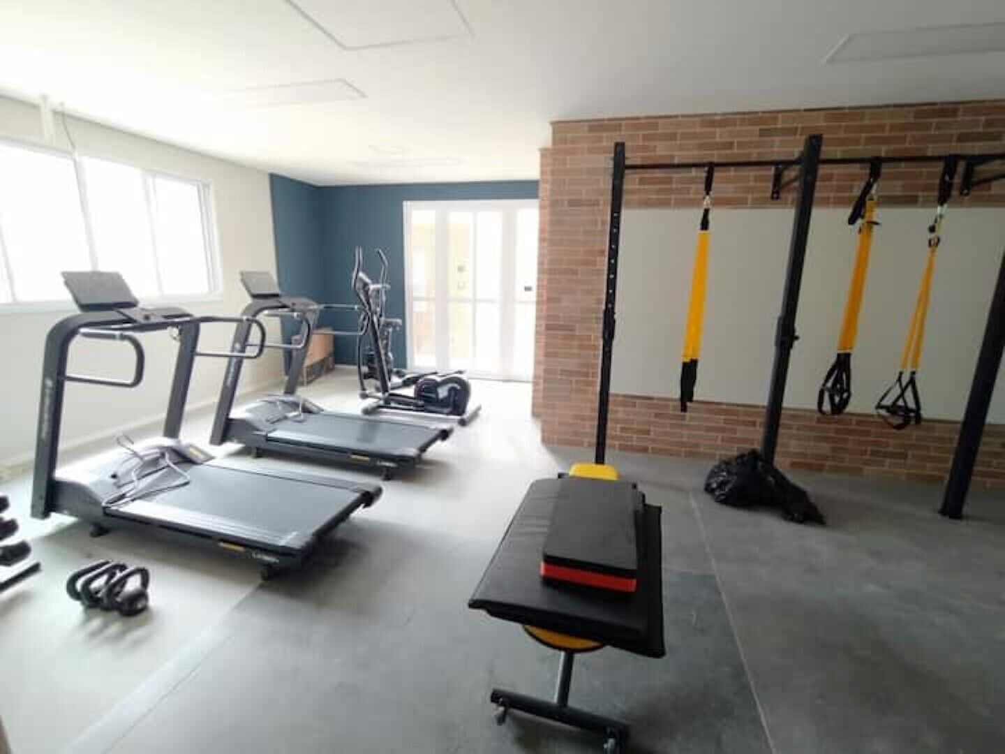 A fitness room with treadmills, elliptical machines, and resistance bands.