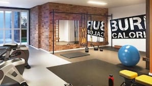 Een sportschool met trainingsapparatuur, een grote spiegel en motiverende muurdecoratie.