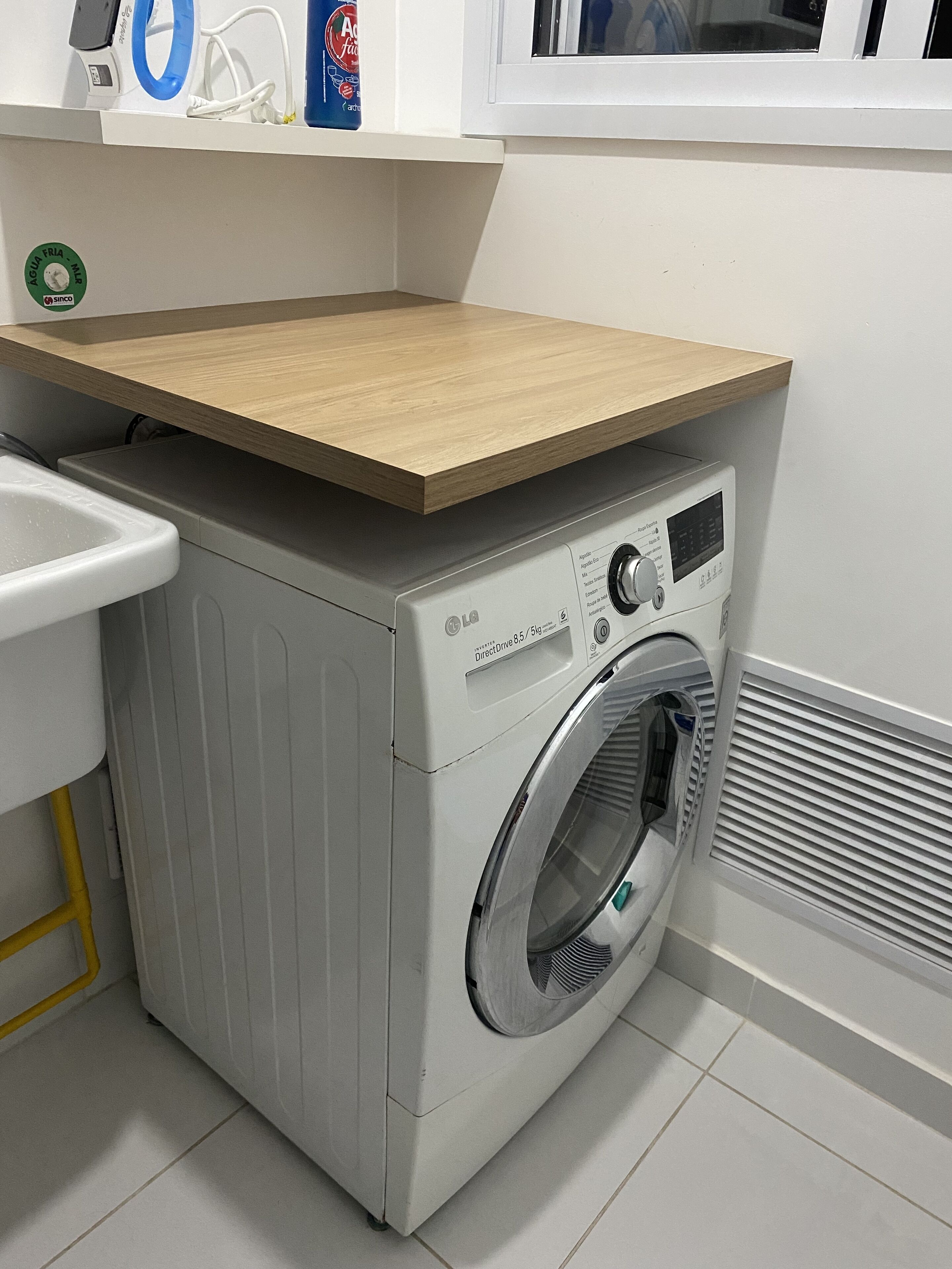 Une petite buanderie moderne, dotée d’un lave-linge et d’un sèche-linge encastrés, d’un plan de travail en bois et d’un évier.