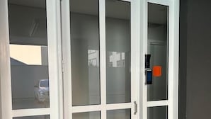 Een witte glazen deur met een handgreep, die uitkomt op een donker interieur.