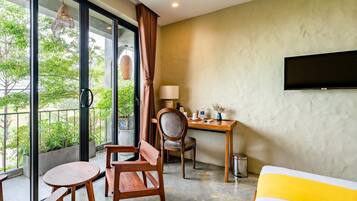 A hotel room with a large window, a desk, a chair, a bed, and a TV mounted on the wall.