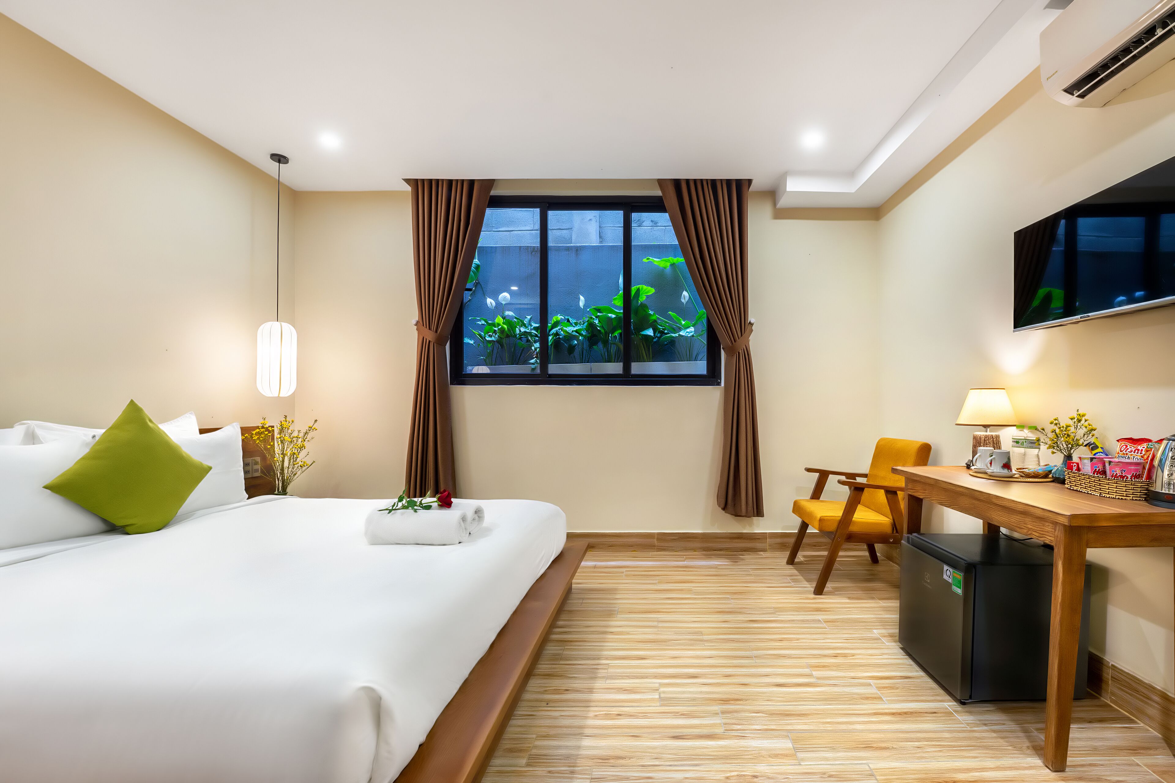 A hotel room with a bed, a desk, a TV, and a window with curtains.