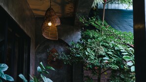 Lluminària penjant en una habitació amb paret de pedra i una planta.