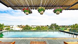 Una piscina exterior amb gandules de fusta i cistells florals penjants.
