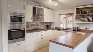A modern kitchen with white cabinets, a Bosch oven, a microwave, a gas stove, and a wooden countertop. - Fellhaven  -  a holiday lodge that sleeps 6 guests  in 3 bedrooms (Windermere)