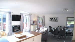 A spacious living area with a kitchen, dining table, and a TV mounted on the wall. - Fellhaven  -  a holiday lodge that sleeps 6 guests  in 3 bedrooms (Windermere)