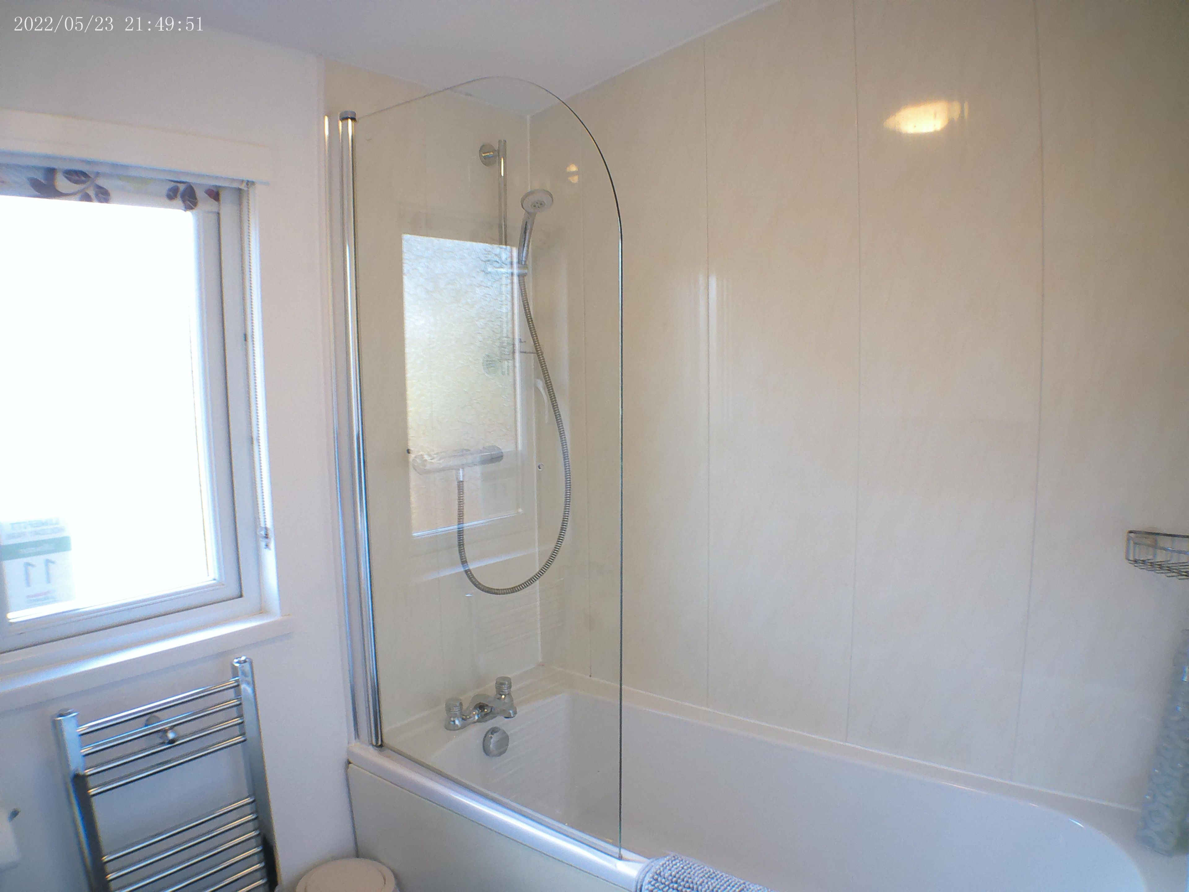 Een moderne badkamer met een douchecabine van glas, een bad en een raam voor natuurlijk licht.