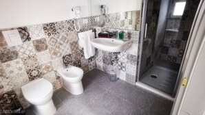 Une salle de bain équipée d’un bidet, de toilettes et d’un espace douche.