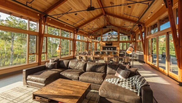 A spacious living area with a large sectional sofa, a wooden coffee table, and a kitchen area with a dining table and chairs. - Ultra Luxury Mountain Retreat | Private Hot Tub + Firepits | Privacy | Summit Sky Ranch (Silverthorne)